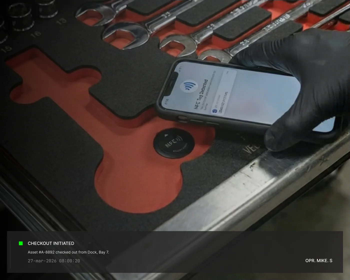 Technician tapping a phone to authenticate a tool checkout from a foam tray.